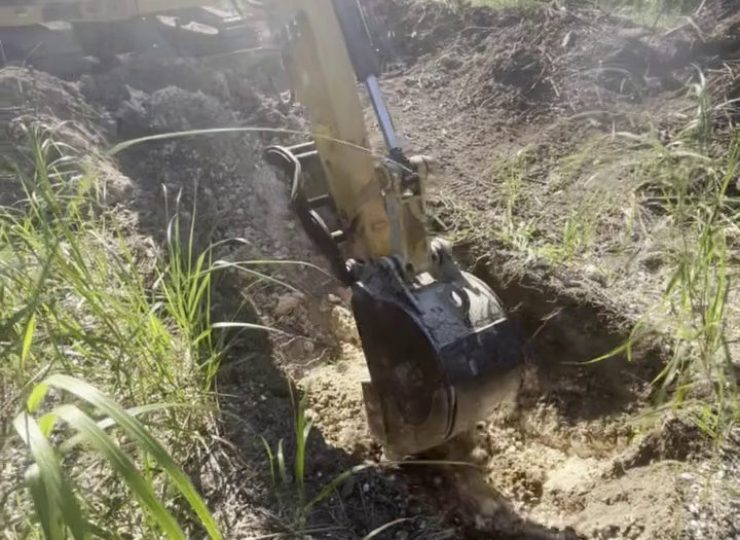 305UGC excavator digging a drain and sewer trench in sandy Florida soil