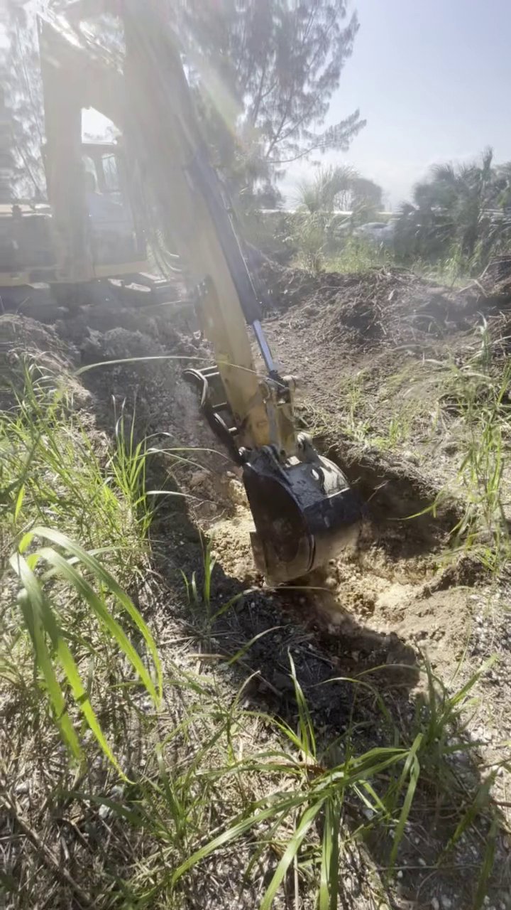 305UGC excavator digging a drain and sewer trench in sandy Florida soil