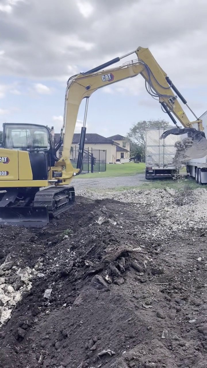 305UGC CAT 308 excavator loading demolition debris near a semi trailer in Miami